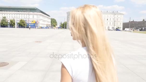 Bela jovem caucasiana caminhando na cidade, vestindo óculos de sol elegantes e jeans curtos, dia ensolarado de verão . — Vídeo de Stock