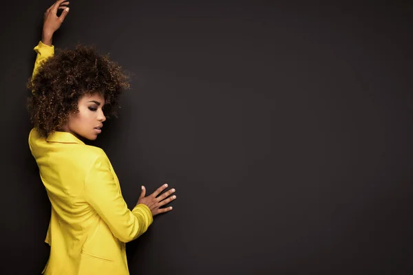 Menina com penteado afro, posando de jaqueta amarela. — Fotografia de Stock
