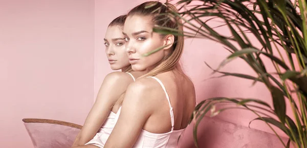 Gyönyörű kaukázusi ikrek női modellek rózsaszín háttér. — Stock Fotó
