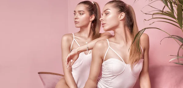 Mooie Kaukasische tweeling vrouwelijke modellen op roze achtergrond. — Stockfoto