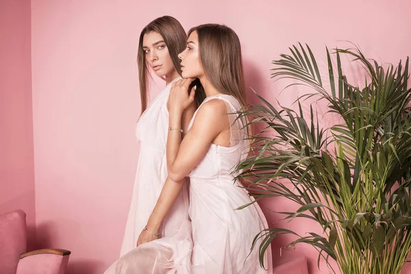 Attraktiva två vackra flickor på rosa bakgrund. — Stockfoto