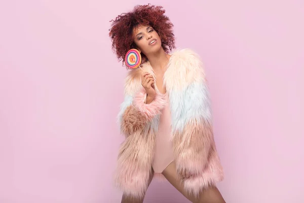 Fashionable afro woman with lollipop on pink background. — Stock Photo, Image