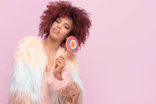 Donna afro alla moda con lecca-lecca su sfondo rosa . — Foto Stock