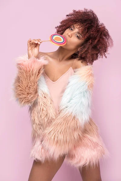 Fashionable afro woman with lollipop on pink background. — Stock Photo, Image