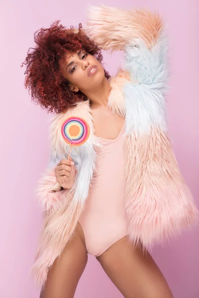 Fashionable afro woman with lollipop on pink background. — Stock Photo, Image