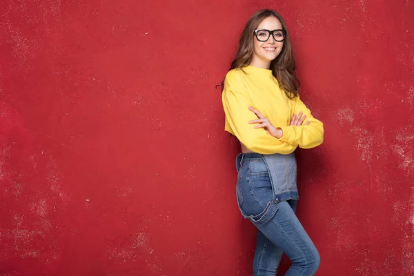 Glücklich lächelndes Mädchen, stehend auf rotem Hintergrund. — Stockfoto