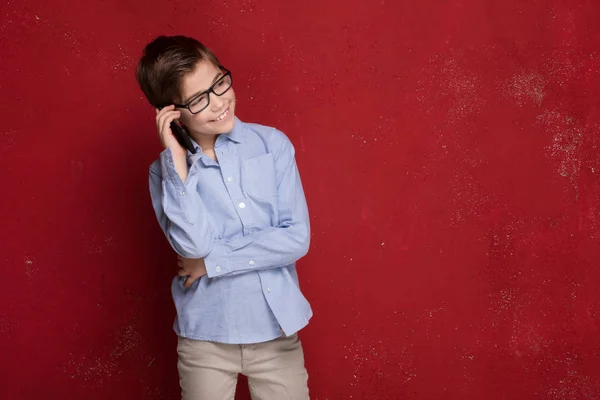 Niño inteligente en anteojos hablando por teléfono móvil . — Foto de Stock