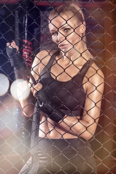 Female boxer posing inside a boxing cage. — Stock Photo, Image