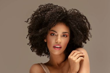 Güzel Afrikalı Amerikalı kadın kameraya bakıyor. Afro saçlı neşeli genç bir kadının portresi. Kıvırcık saçlı güzel kız..