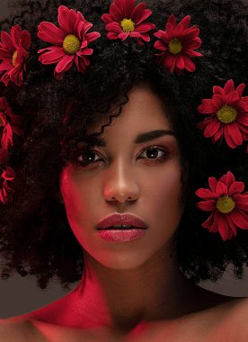 Saçında güzel çiçekler olan çekici bir afro kadın. Güzellik stüdyosu portresi.