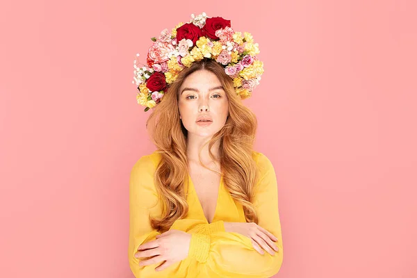 長い波状の髪を持つ幸せな春の女性の美しさの写真 パステルピンクのスタジオの背景にポーズをとった花を持つ赤い髪の女の子 人間の感情表現の概念 — ストック写真
