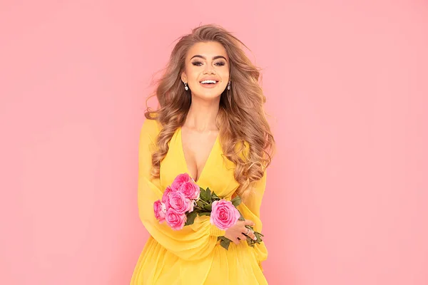 若いです幸せな笑顔ブロンド女性保持花束のカラフルな春の花のピンクパステルの背景に隔離 — ストック写真