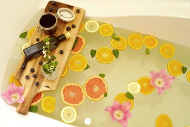Greyfurt, limon ve portakal dilimleriyle rahatlatıcı bir banyo. Ahşap tahta üzerinde güzellik ürünleri. Refah kavramı