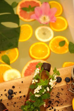 Greyfurt, limon, portakal dilimleri ve çiçeklerle rahatlatıcı bir banyo. Güzellik tedavisi. Sağlık, sıfır atık kavramı.