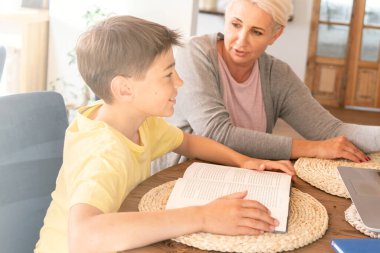 Beyaz bir anne evdeki internet dersinde oğluna yardım ediyor..