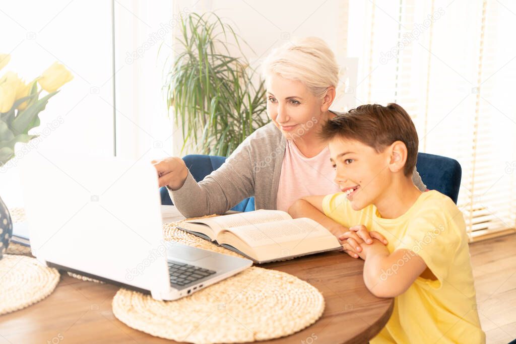 Caucasian mom helping son with online lesson at home.