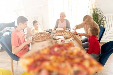 Aile evde birlikte güzel vakit geçiriyor. Kızlı ve çocuklu anne eğleniyor, pizza yiyor. Ev konforu. 