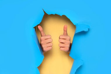 Başparmaklar yukarı. Mavi stüdyo arka planında bir sürü kopya alanı var. Tamam işareti olan eller..