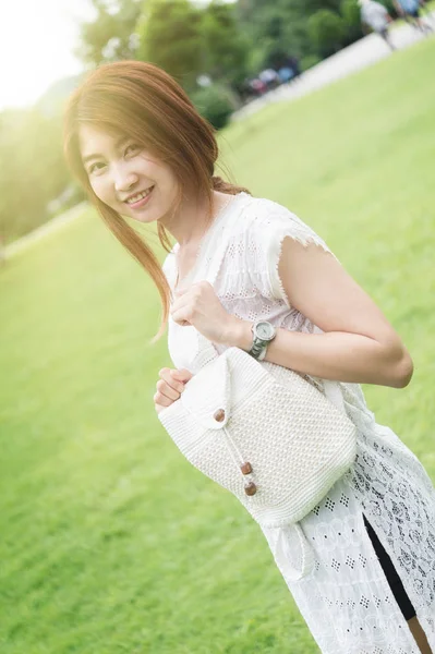 亚洲的年轻女孩与袋站在公园上的肖像 — 图库照片