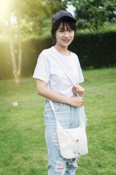 Ritratto di asia giovane ragazza con borsa in piedi sul parco — Foto Stock