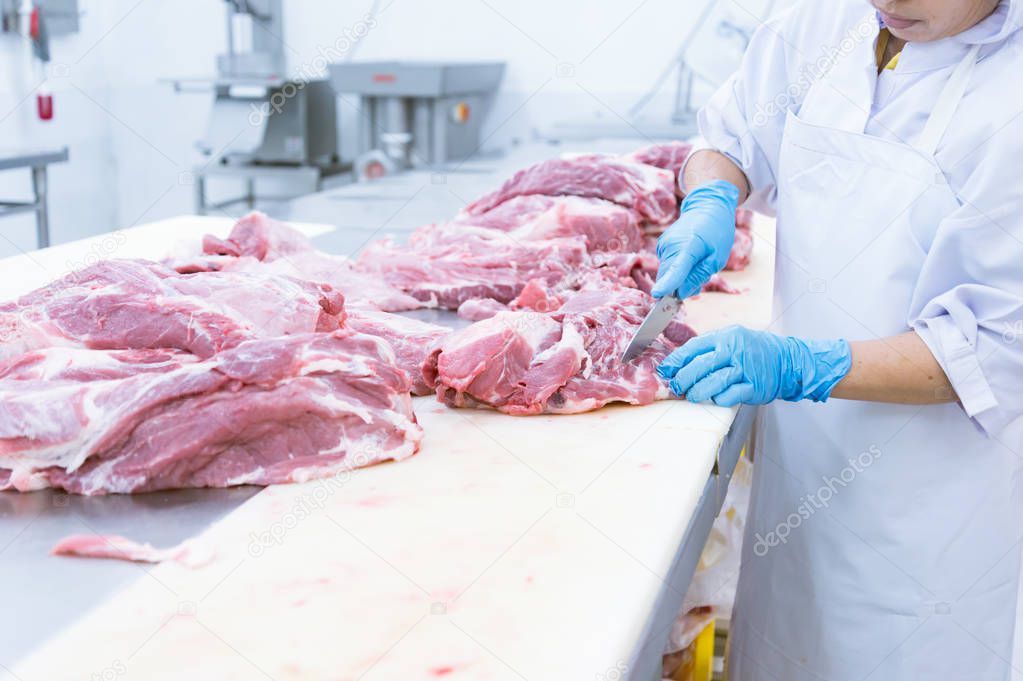butcher cutting the fresh meat in ham factory