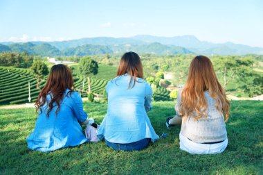 Üç Asya kız oturup çay bahçesi yeşil çimenlerin üzerinde 