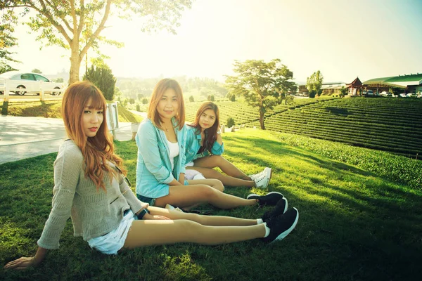 Τρεις Ασίας κορίτσι κάθονται στην πράσινη χλόη στο κήπο τσαγιού — Φωτογραφία Αρχείου