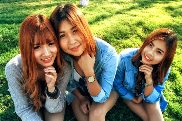 Três asiático sorriso menina sentar na grama verde — Fotografia de Stock