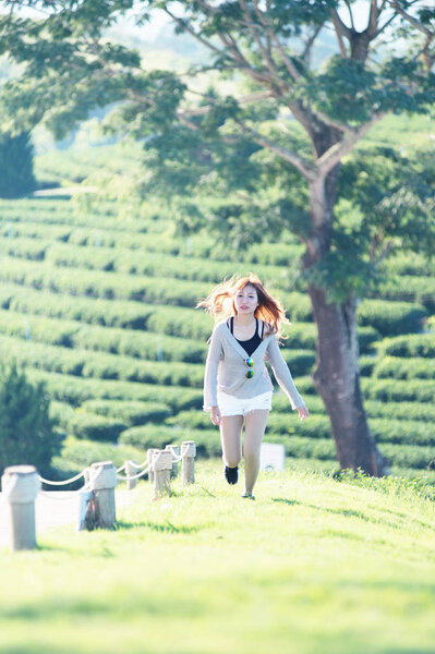 asia woman running on green grass at chuifong tea garden in Chiangrai Thailand