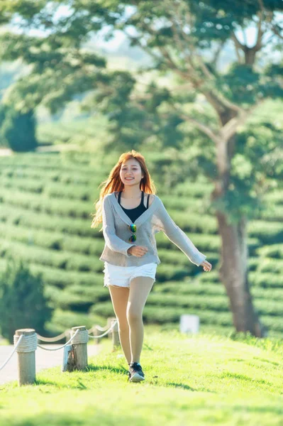 Mujer asia corriendo sobre hierba verde en el jardín del té —  Fotos de Stock