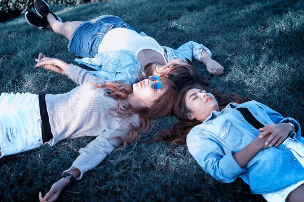 Drei asiatische glückliche Mädchen liegen mit Sonnenbrille auf grünem Gras — Stockfoto