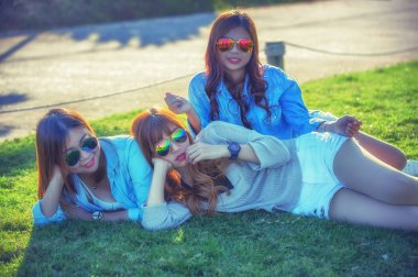 Üç Asya kız çay çiftliğinde yeşil çim üzerinde yalan 