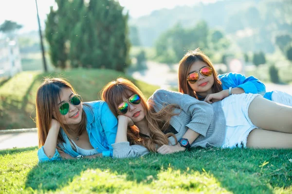 Üç Asya kız çay çiftliğinde yeşil çim üzerinde yalan 