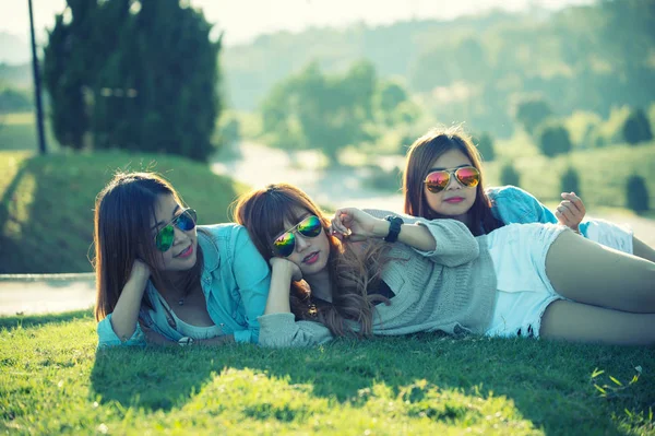 三个亚洲女孩笑着躺在翠峰茶园的草地上 享受着闲暇 放松的生活 — 图库照片