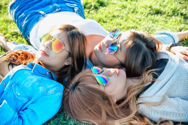 Trzy dziewczyny happy Asia, leżącego na zielonej trawie w okulary — Zdjęcie stockowe