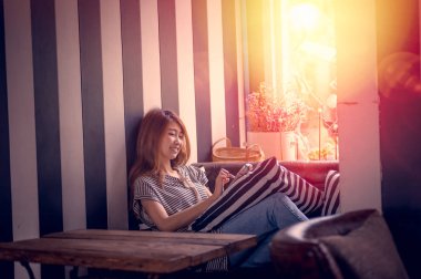 cep telefonu kullanarak ve kanepe evinde yatarken Asya kadın