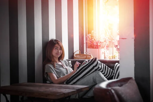 Asiatische Frau mit Handy auf dem Sofa in ihrem Haus — Stockfoto