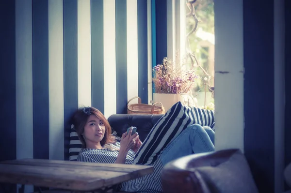 Азия женщина с помощью мобильного телефона на диване в своем доме — стоковое фото