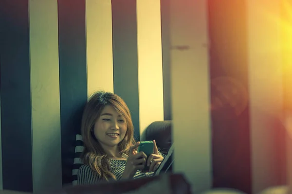 Asia woman using cell phone on sofa in her home — Stock Photo, Image