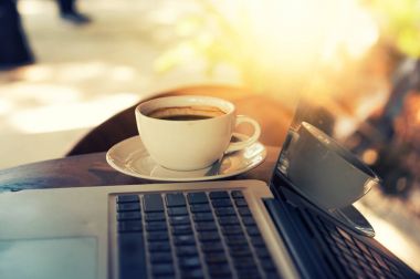 Tahta masada bir fincan kahve ve dizüstü bilgisayar.