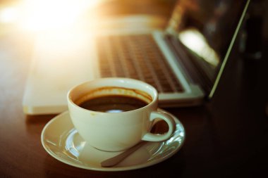 Tahta masada bir fincan kahve ve dizüstü bilgisayar.