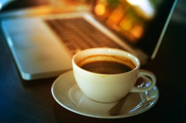 Tahta masada bir fincan kahve ve dizüstü bilgisayar.