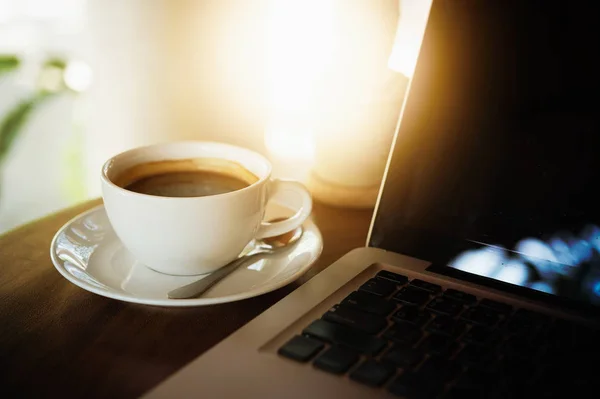 Tahta masada bir fincan kahve ve dizüstü bilgisayar. — Stok fotoğraf