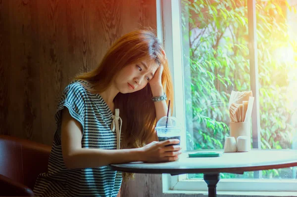アジアの美しい女性がコーヒー ショップでリラックスします。 ロイヤリティフリーのストック画像