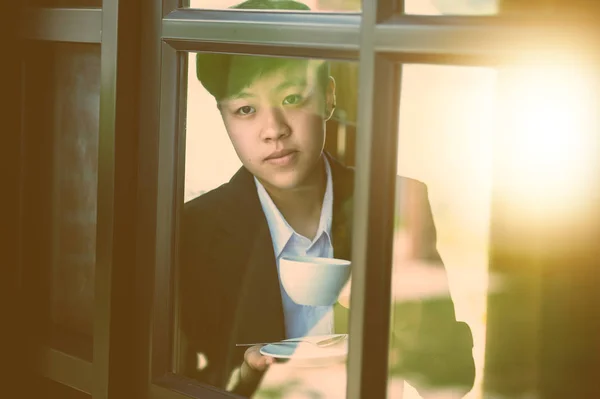 asia businessman standing near office window and drinking coffee