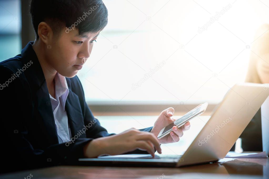Businesspeople using laptop and holding smartphone in office