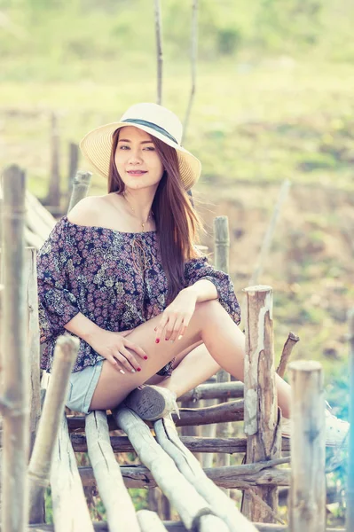 asia woman in Off  Shoulder shirt and short jeans with hat sitting on nature