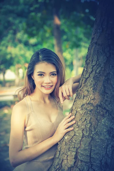 Asiatico donna in piedi sdraiato albero in parco su sole — Foto Stock