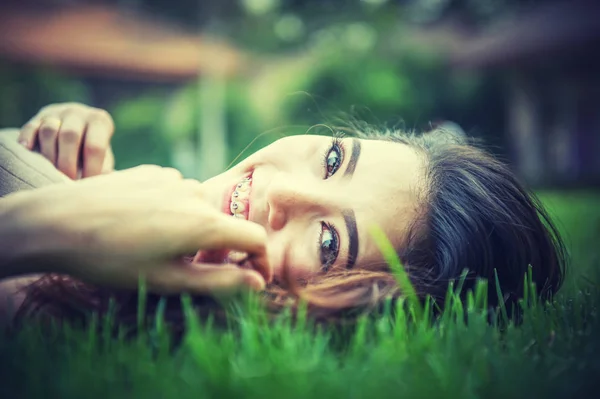 Девочка лежит на зеленой траве, отдыхая в парке . — стоковое фото