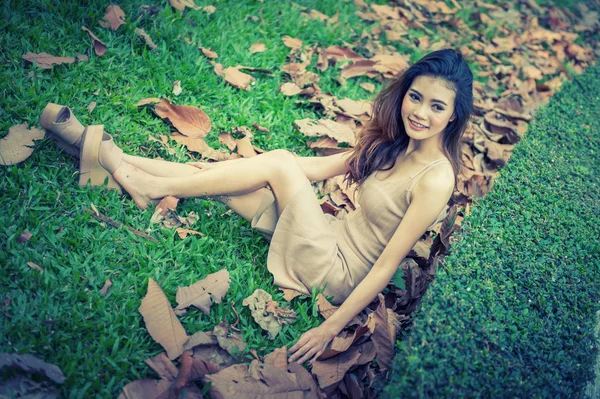 亚洲漂亮的女孩坐在公园的绿色的草地上的肖像 — 图库照片